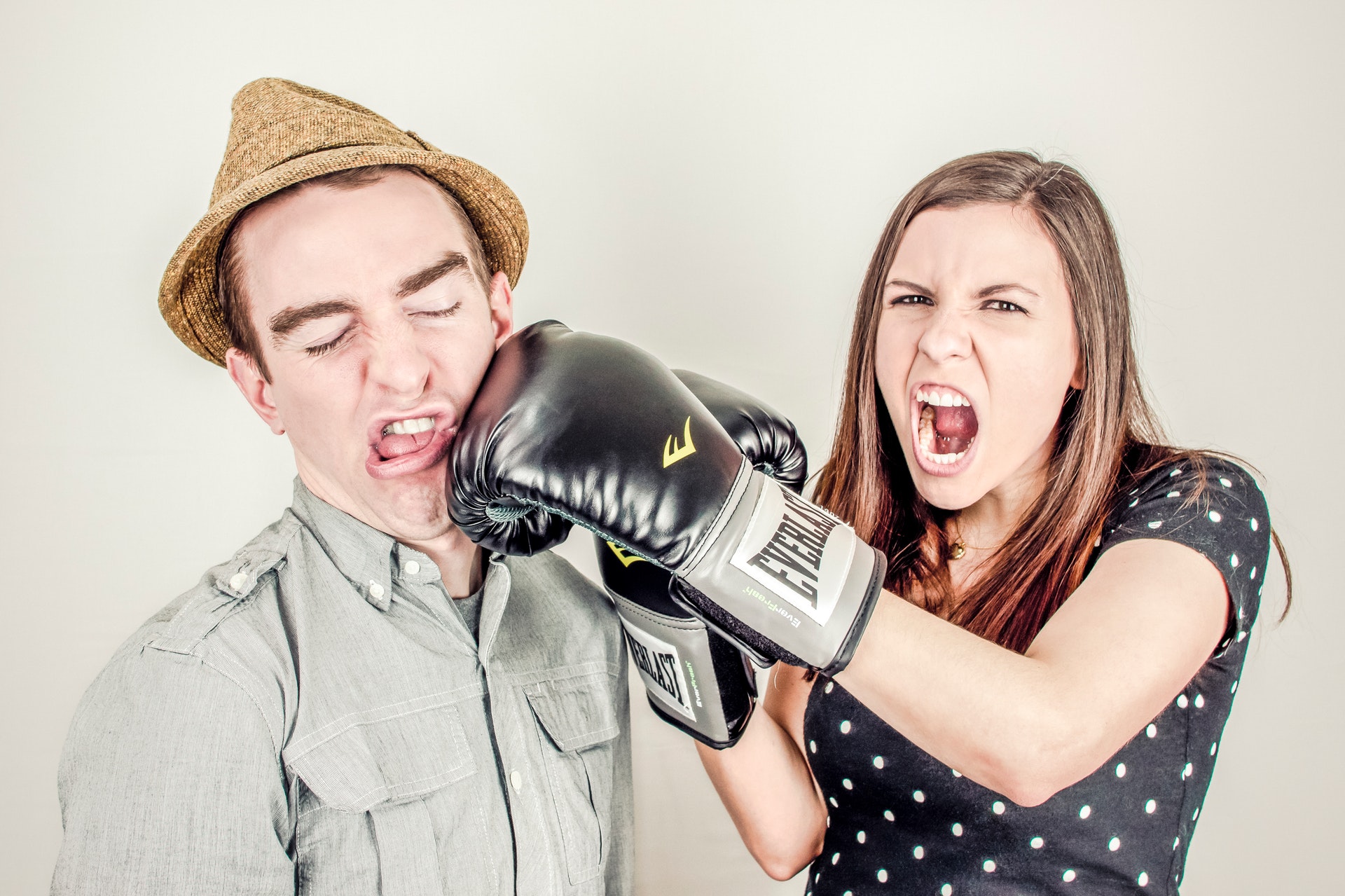 Woman wearing boxing gloves punching man in face.